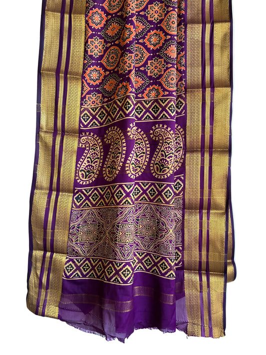 Close up of soft breathable purple fabric featuring delicate floral medallions and gold tone border