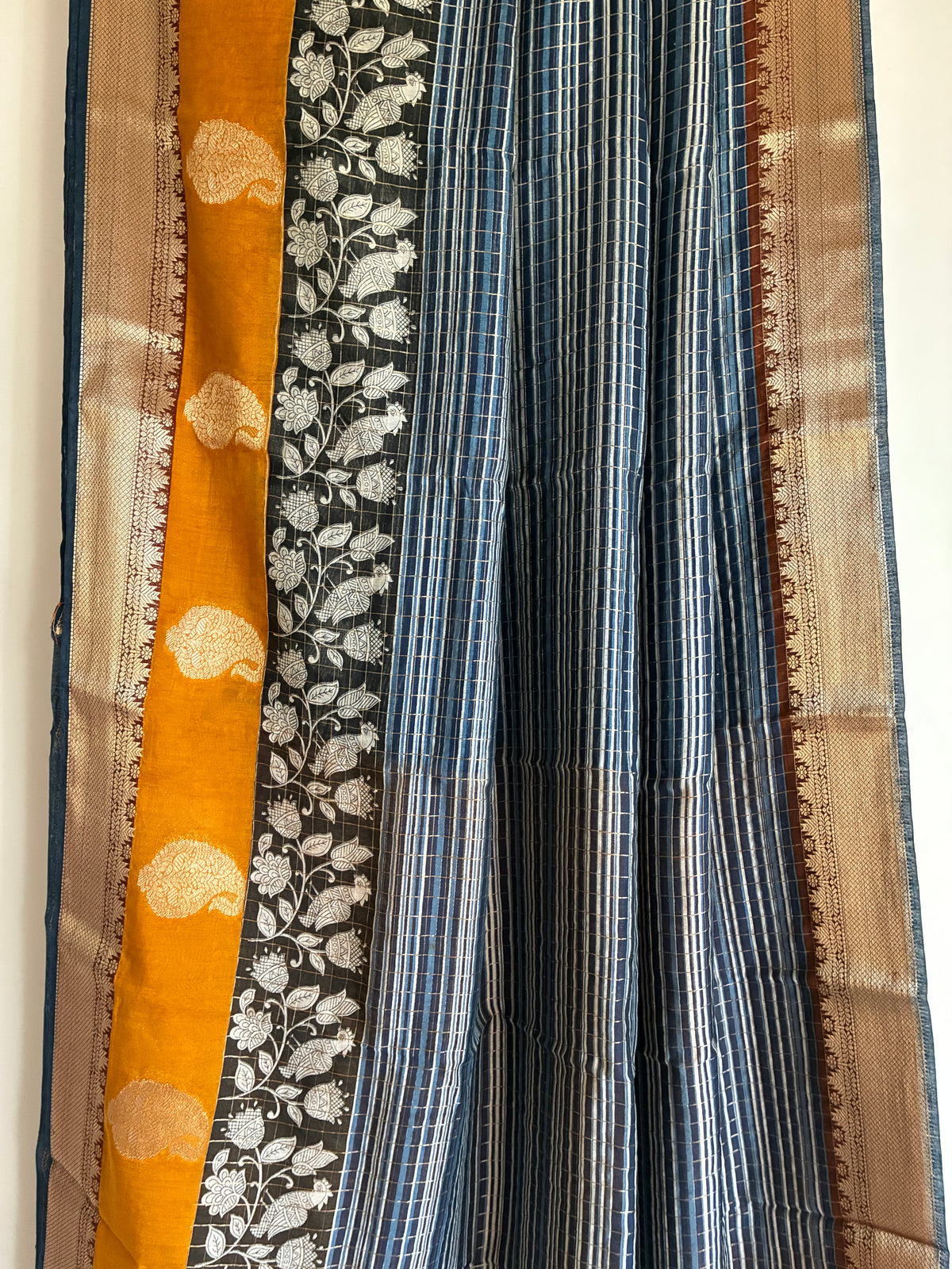 Detailed view of rich Assam silk saree pallu featuring black Kalamkari floral vines and mustard accents