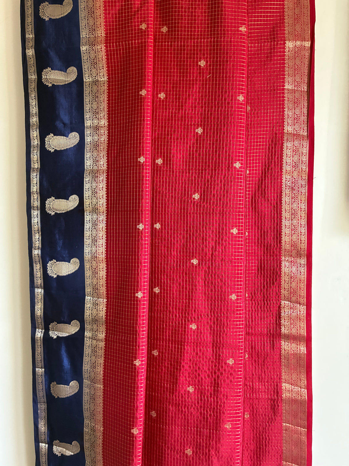Close up of soft breathable red checked saree fabric with blue border and traditional mango motifs