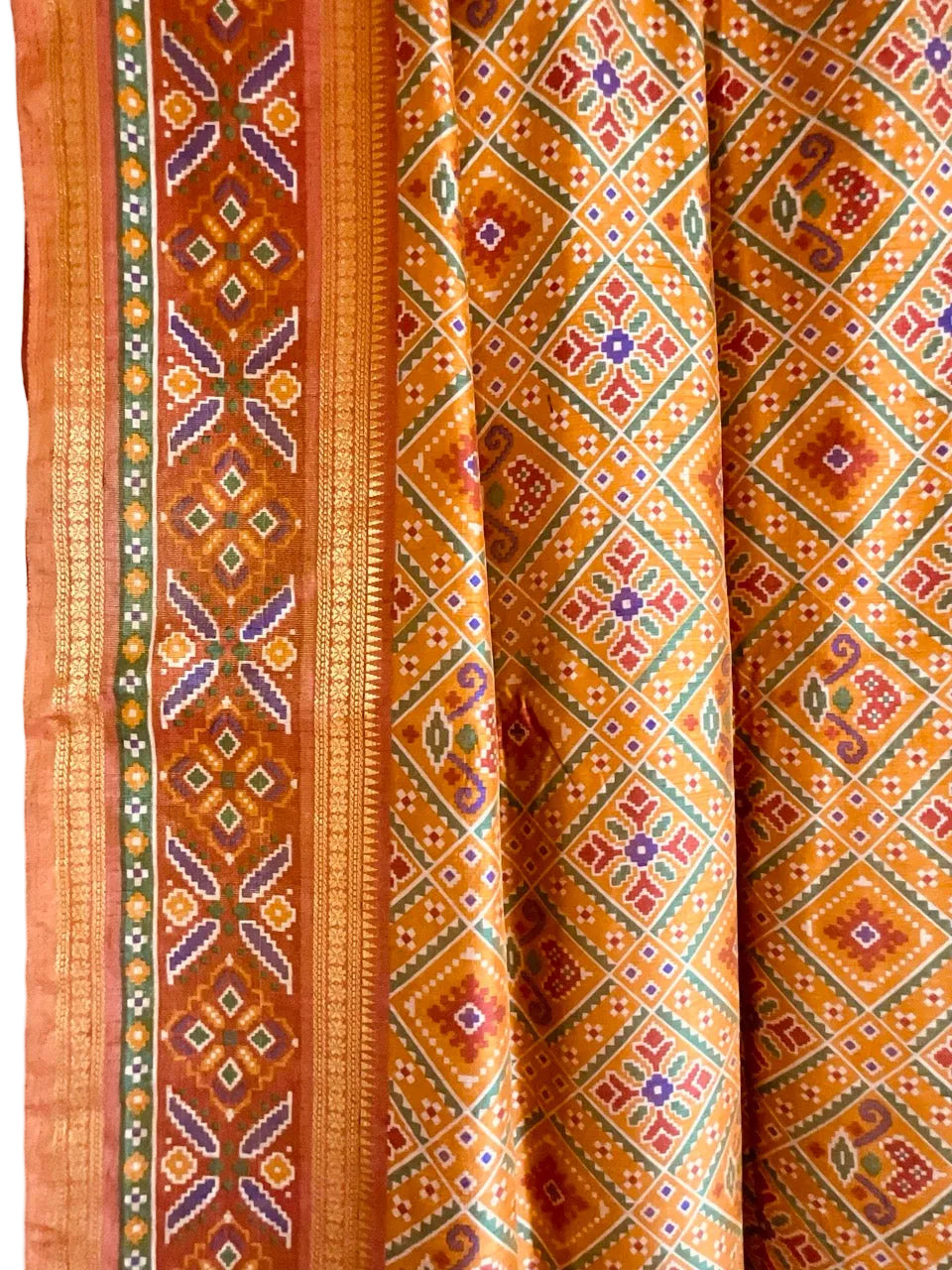 Patola saree in orange and brown tones on a plain background