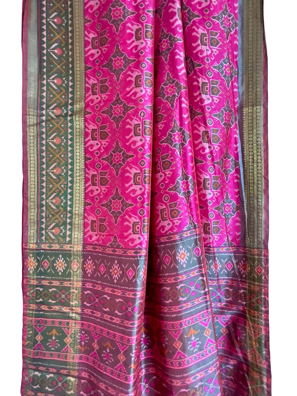 Traditional patterned fabric with pink and green colors on a light blue background