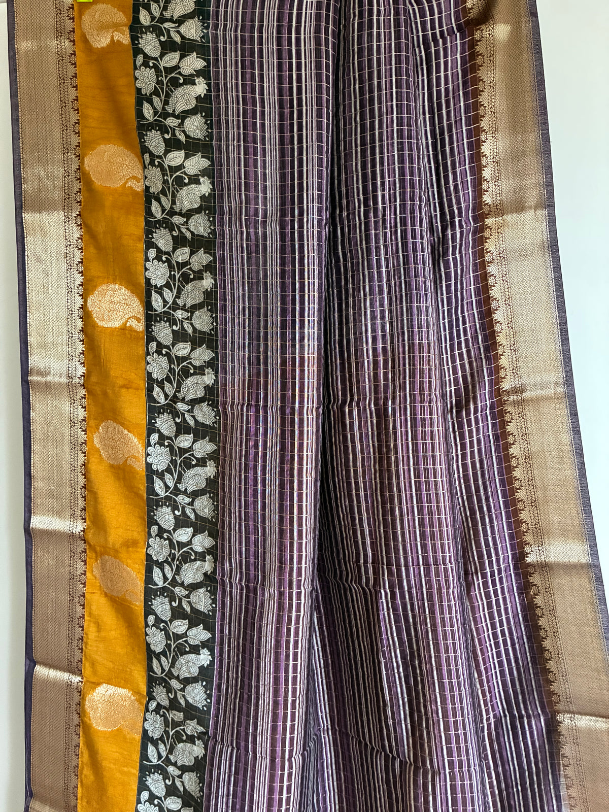 Close up of soft breathable purple Assam silk fabric with fine stripes and gold-toned detailing