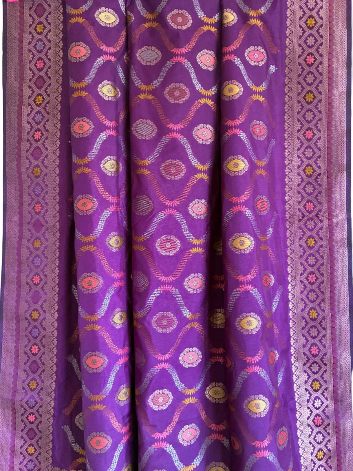 Close up of soft breathable purple silk weave featuring intricate floral vine patterns and metallic border
