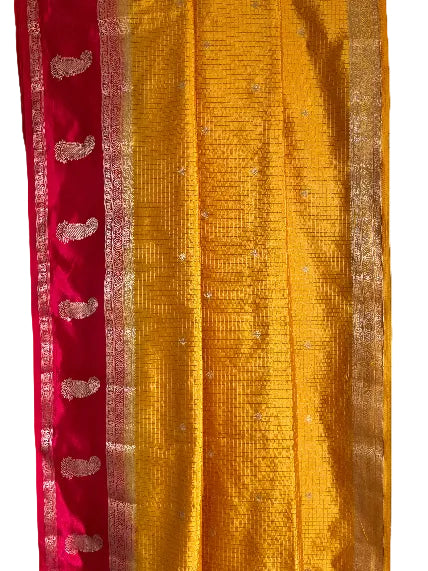 Close up of soft breathable yellow checked saree fabric with red border and traditional mango motifs