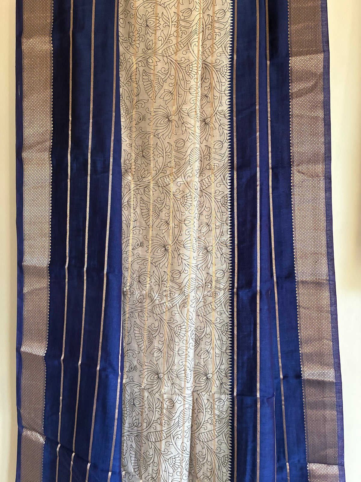 Close up of royal blue saree weave featuring white floral Kalamkari print and fine golden stripes