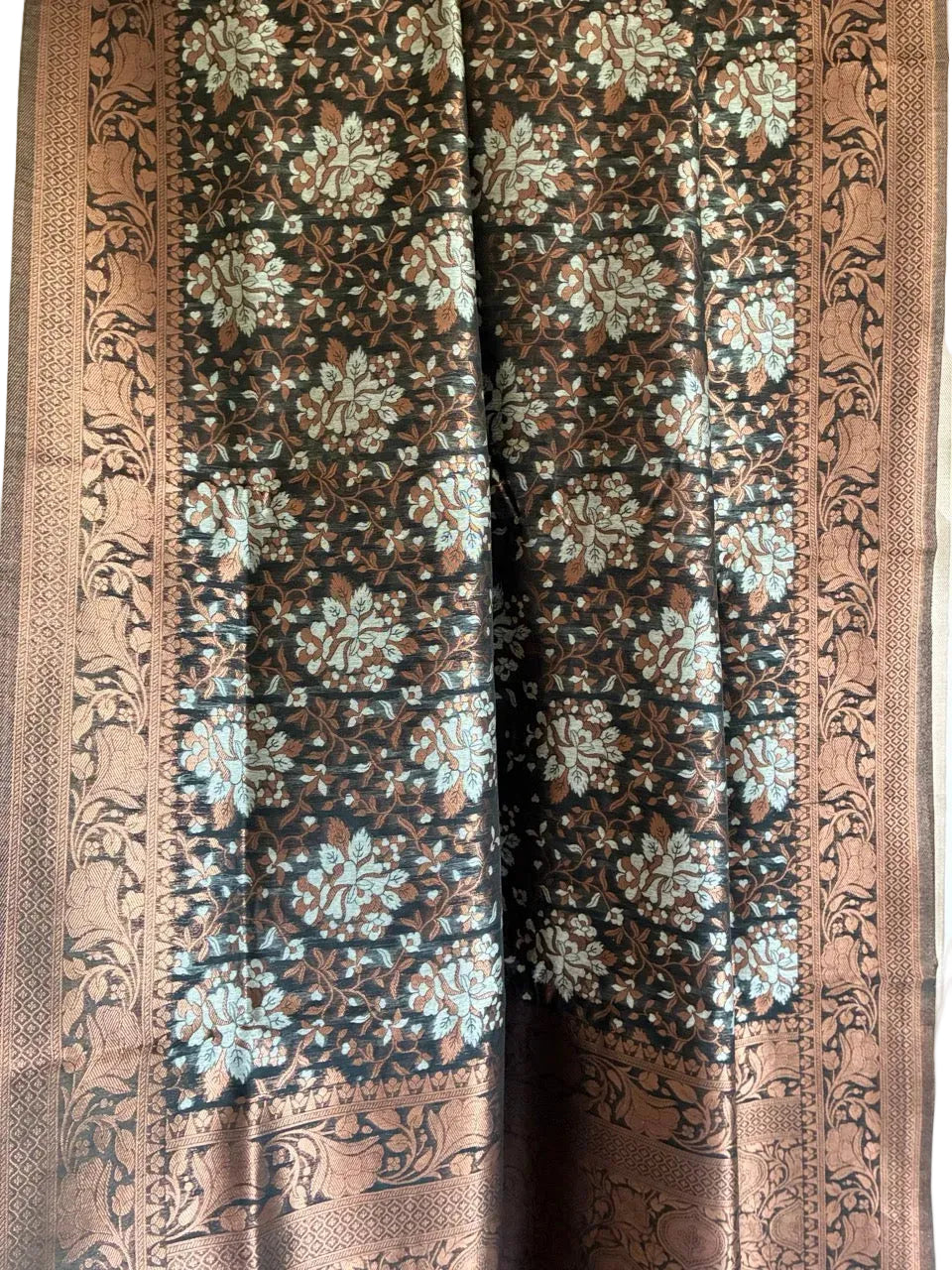 Close up of soft breathable metallic black fabric with fine warm copper floral weave and ornate border
