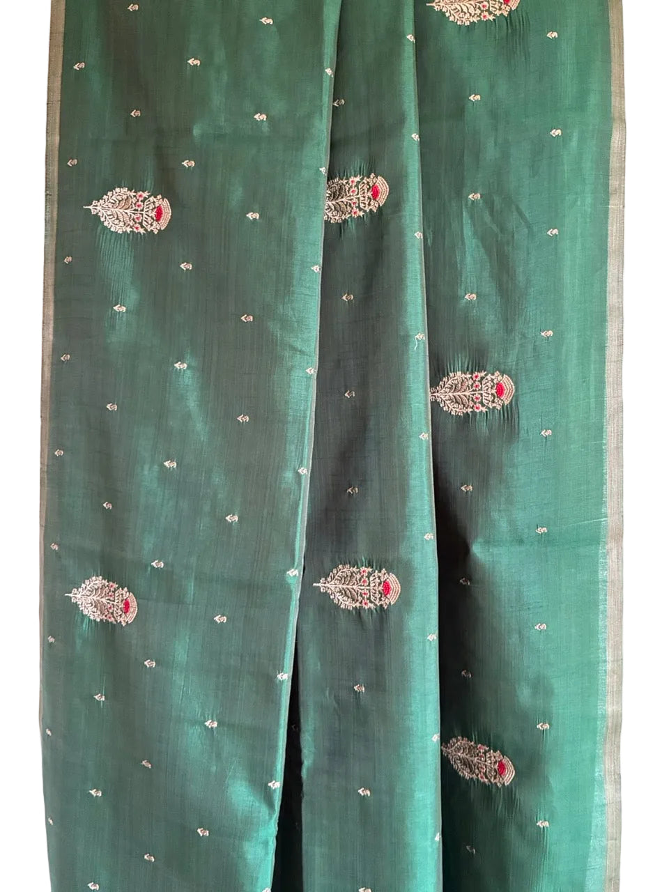 Close up of soft breathable green saree fabric showing delicate embroidery detail