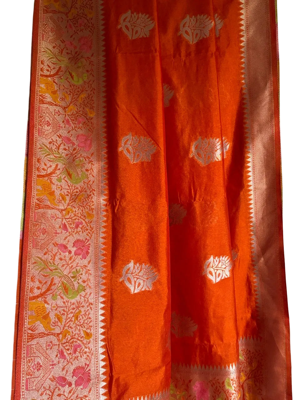Close up of soft breathable orange fabric featuring gold elephant and bird motifs with broad border