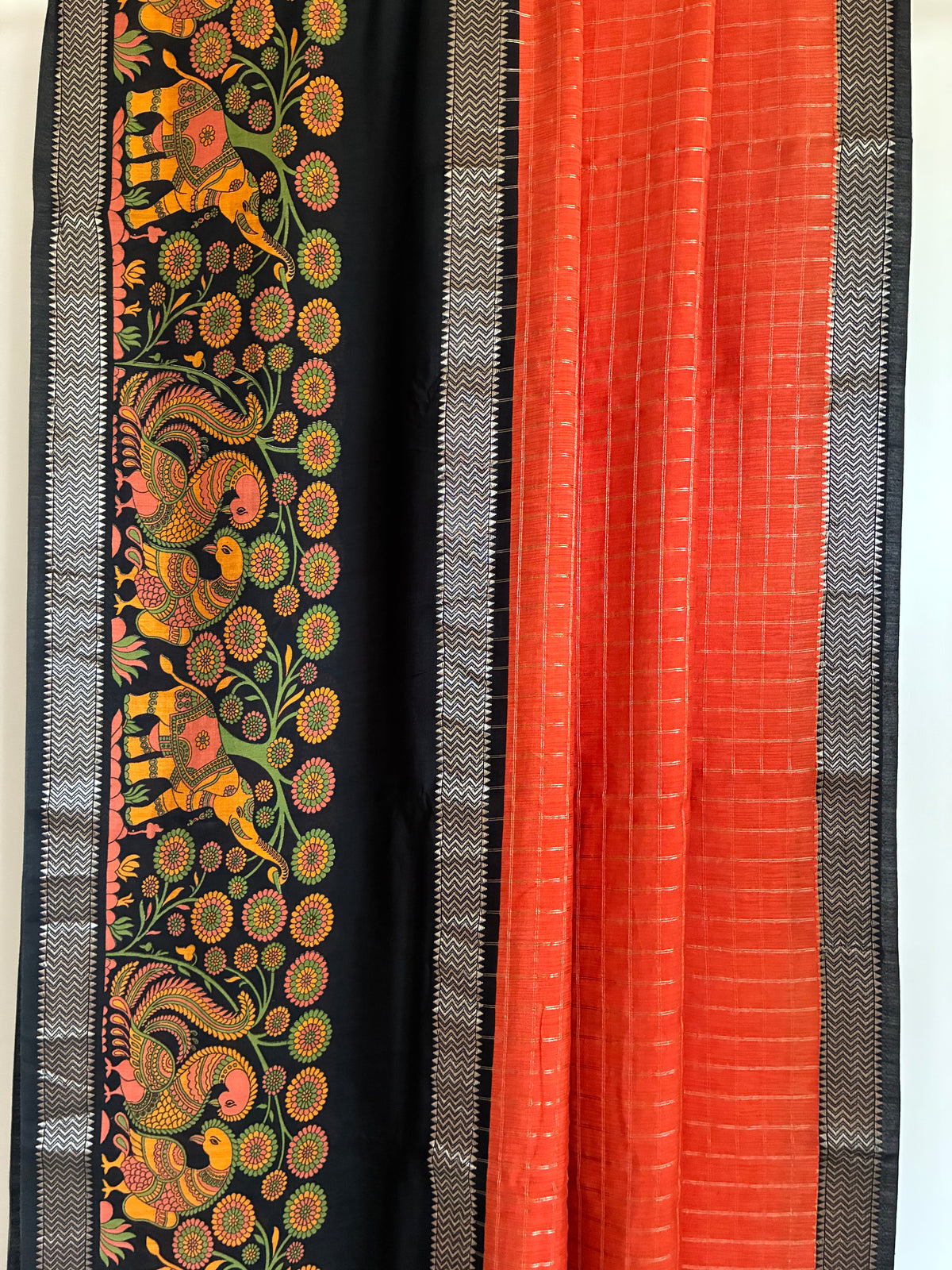 Close up of soft breathable orange Kalamkari fabric featuring contrast black border design