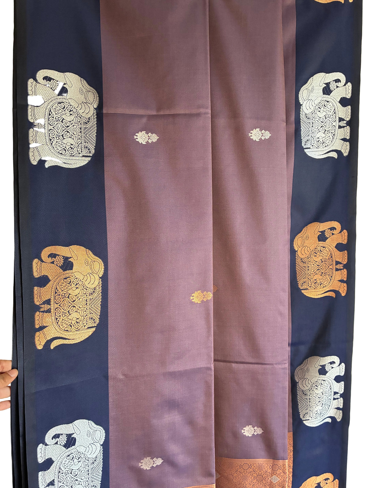 Close up of soft breathable fabric with gold and silver tone ornate elephant weave on navy border