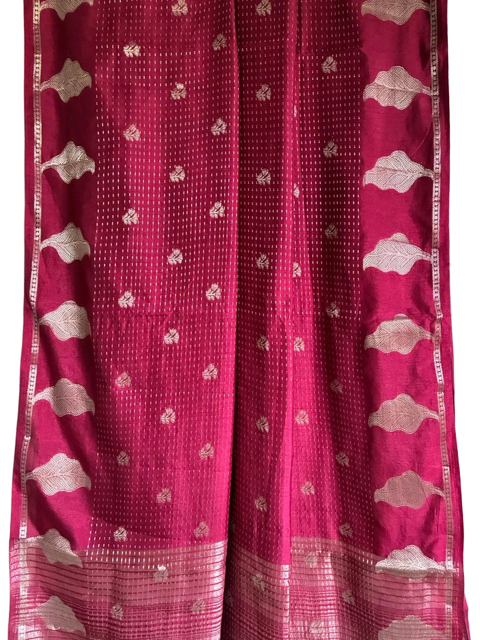 Close up of soft breathable red saree fabric with fine gold dotted weave and leaf border design